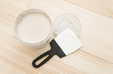 Spatula and a bucket of white putty on wooden boards. Top view Copy space