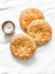 Small focaccia tortillas with sea salt on a light background, top view