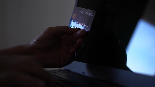 hacker with credit card, theft holding credit cards on laptops using data password in unauthorized shopping for payments, hacking in cyber crime security concept