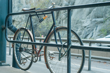 Obraz premium Old road bike attached to the fence next to the highway.
