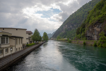Fototapeta na wymiar Beautiful view of aare river through the interlaken on cloudy sky with sunlight and fresh green mountain background with copy space