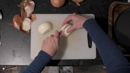 First person view of chopping a white onion on a chopping board