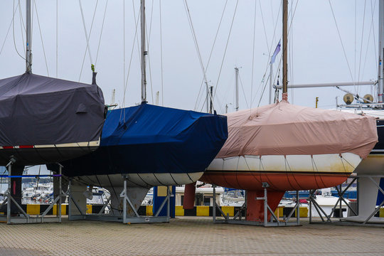   Yachts are on the shore. The yachts are covered with a tarp.   Wintering yachts.