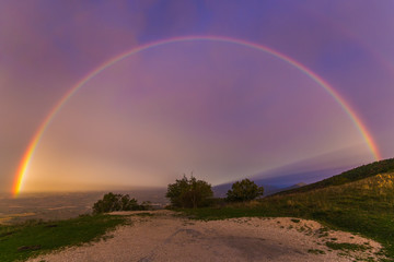 Fototapeta na wymiar View of wonderful rainbow at sunrise on rainy day in the italian mountain