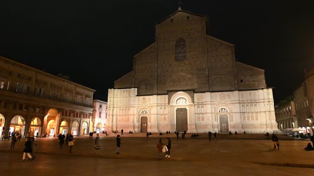 Bologna, Italy - October 2019 - Unknown people walk in the evening among the buildings and monuments of the historic city center, followed by the shadows of the night