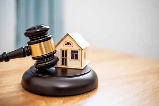 Lawn auction hammer and small house on the table, real estate mortgage auction
