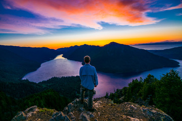 Fototapeta premium Adventurous man watching a sunset from a mountaintop.