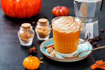 Pumpkin spice latte in a glass mug with cinnamon and nutmeg .