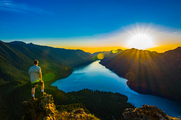 Adventurous man watching a sunset from a mountaintop.