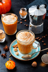 Pumpkin spice latte in a glass mug with cinnamon and nutmeg .