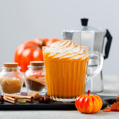 Pumpkin spice latte in a glass mug with cinnamon and nutmeg .