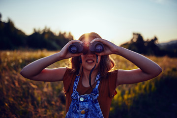 Little girl using binoculars in the nature.