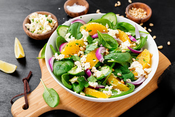 Fresh spinach salad with oranges, feta (ricotta) cheese, red onion and pine nuts .