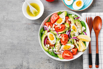 Fresh avocado salad with tomato,cucumber , boiled eggs and spinach served with lemon and ricotta cheese. Top view.