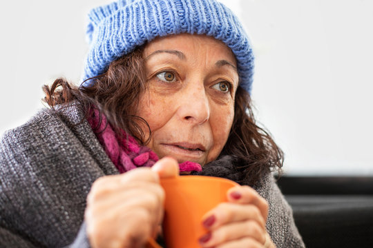 An elderly homeless woman with a cup of soup