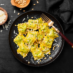 Italian ravioli pasta with spinach and ricotta on black wooden  background. Top view.