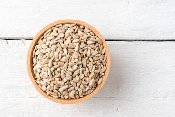 Peeled sunflower seeds in bowl on rustic wooden table. Top view