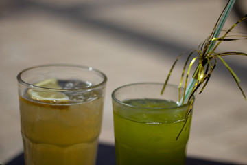 Green and yellow fruit cocktails isolated summer sunny day brown coffee table