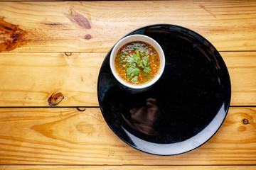 A black plate on a wooden table with seafood sauce, top view