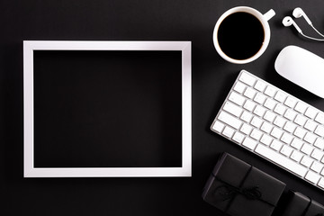 White picture frame with keyboard mouse coffee cup, gift box and Christmas tree decoration on black...