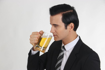 Businessman drinking beer, white backdrop.