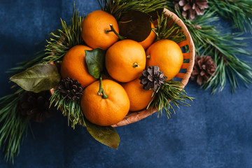 Tangerines in a wooden basket decorated with pine branches