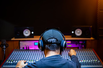 back of asian male professional music producer, sound engineer mixing a song on audio mixing console in recording studio. music production, post production concept - 301535076