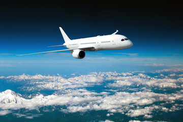 White passenger plane in flight. The plane flies above a snow covered mountain landscape. Aircraft...