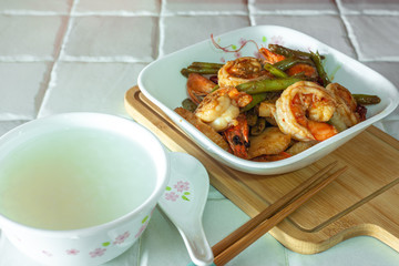 Stir-fried spicy dried chilli french green beans with prawns, and a bowl of porridge.