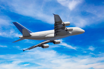 Passenger aircraft view from behind. The plane flies away in the blue sky.