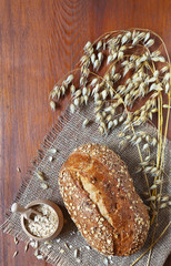 Helpful oat bread, oatmeal and ears of oat on a wooden background. Healthy simple fare with dietary fiber. Rustic still life. Flat lay, top view, close-up, space for text.