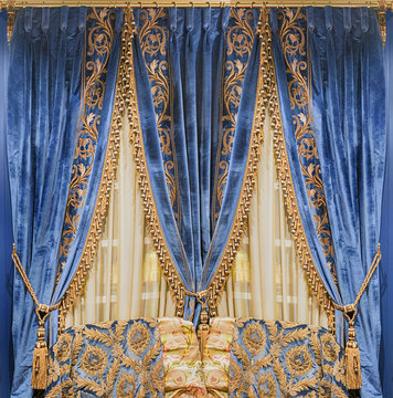 Luxurious blue velvet curtains, embroidered with gold ornaments and fringe