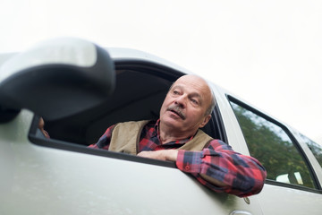 Senior old hispanic man looking out of car being sad and irritated because of traffic jams
