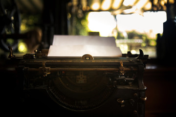 Pure white paper is in an old black rustic typewriter. The typewriter is ready for the writer to...