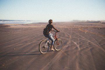 Fototapeta na wymiar woman on a bike at the beach during sunset
