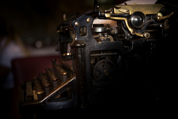Selective focus on the keyboard and mechanism of an old black rustic typewriter on an office desk.