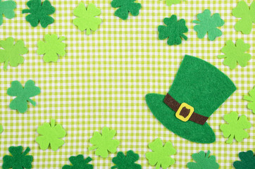 Flat lay Happy St. Patrick's background mockup of handmade felt shamrock clover leaves and hat on...