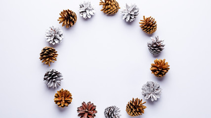 Painted pine cones frame on light grey background, Christmas golden and silver decorations flat...