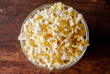 Top view of Popcorn in a glass cup on a wooden table.