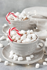 Gray  mugs filled with hot chocolate and marshmallows decored candy cane