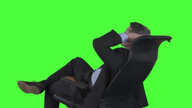 Side view of Caucasian businessman sitting on the office chair while thinking idea or daydreaming. Shot in 4k resolution with green screen background