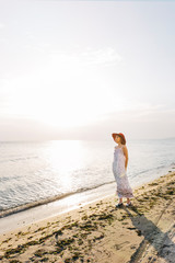 Female model with white dress and a red hat, she is enjoying beach and sunset