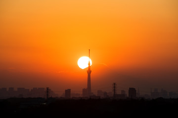 Fototapeta premium Sun setting behind Tokyo Skytree and Mount Fuji in autumn, from Chiba Prefecture, Japan