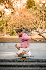 Boy standing on the one knee on the balance board on the concrete steps in the park