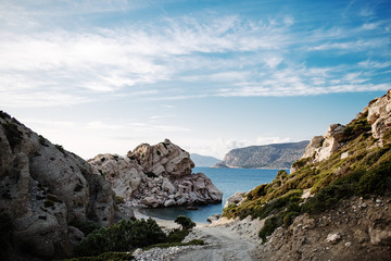 Panorama with a beautiful bay, stone beach and clear blue water. Boat on the bay on Rhodes island, Dodecanese, Greece.