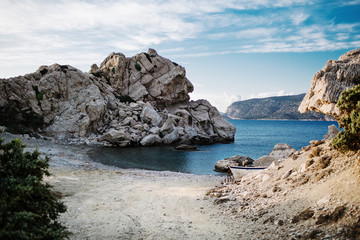 Panorama with a beautiful bay, stone beach and clear blue water. Boat on the bay on Rhodes island, Dodecanese, Greece.