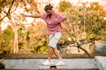 Man balancing on the balance board on the concrete steps in the park