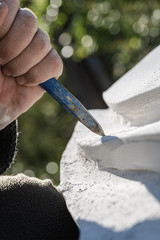 Closeup of an artist working in white stone