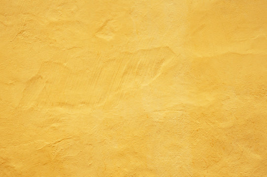 Plain bright yellow plain background. Part of the stone concrete wall surface painted yellow colorful color.