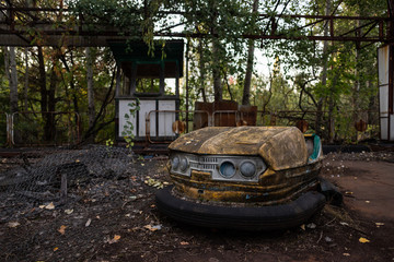 Old abandoned bumper car surrounded by leaves